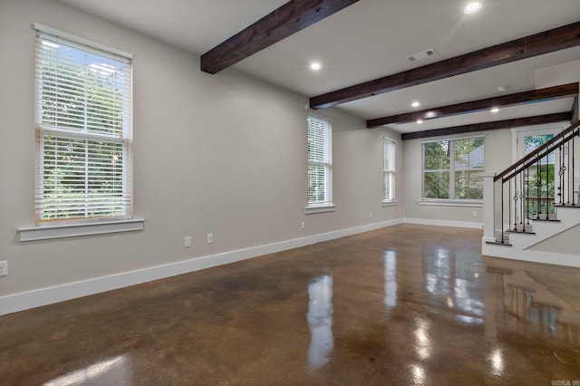 unfurnished living room with concrete flooring, a wealth of natural light, and beamed ceiling