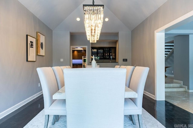 dining area with lofted ceiling, dark hardwood / wood-style flooring, and an inviting chandelier