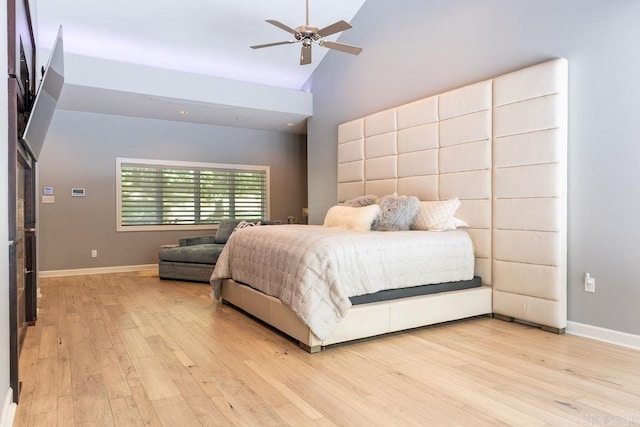 bedroom with ceiling fan, high vaulted ceiling, and light hardwood / wood-style flooring