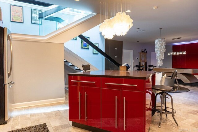 kitchen with decorative light fixtures, a chandelier, a center island, a kitchen breakfast bar, and stainless steel fridge