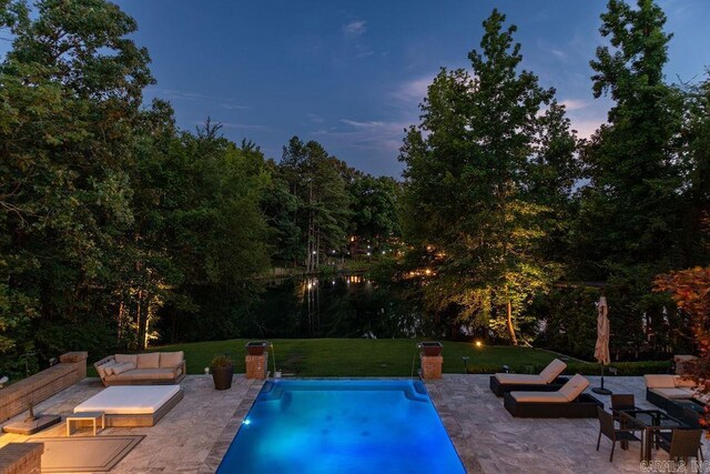 pool at dusk with a patio, a yard, and an outdoor hangout area