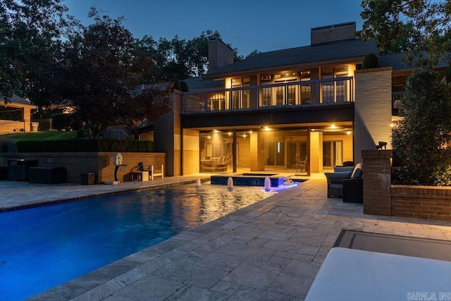 exterior space with a swimming pool with hot tub, a balcony, and a patio area