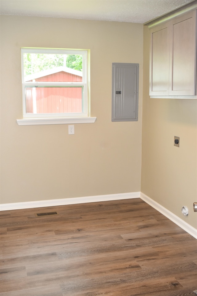 laundry room with hardwood / wood-style flooring, a textured ceiling, electric dryer hookup, cabinets, and electric panel