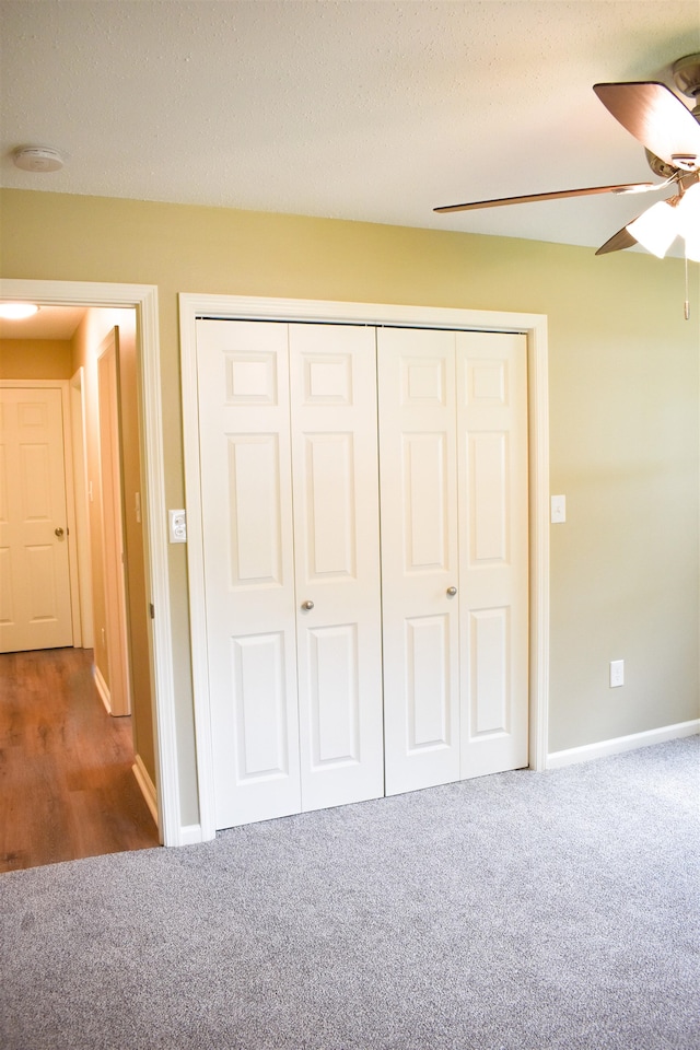 unfurnished bedroom with ceiling fan, carpet floors, a closet, and a textured ceiling