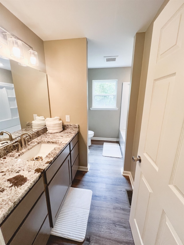 bathroom featuring vanity, a bathtub, toilet, and hardwood / wood-style flooring