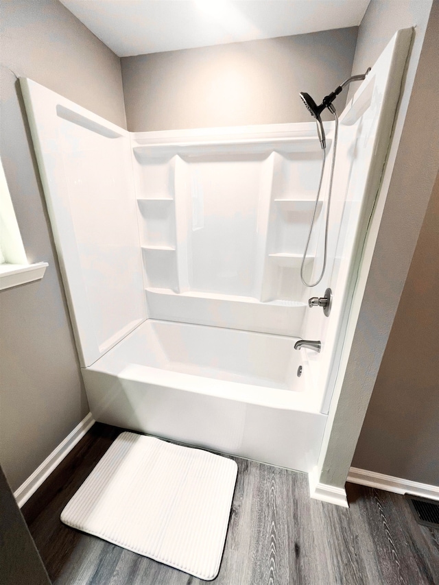 bathroom with hardwood / wood-style flooring and tub / shower combination