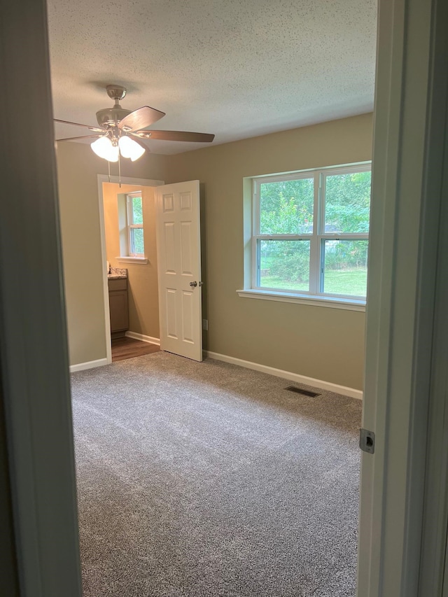 unfurnished bedroom featuring a textured ceiling, carpet flooring, and ceiling fan