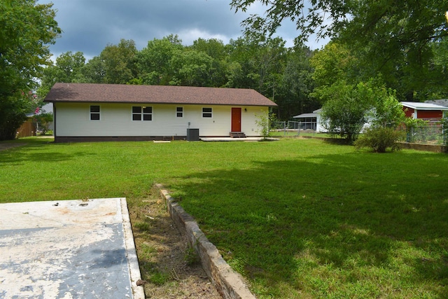 rear view of house with cooling unit and a lawn