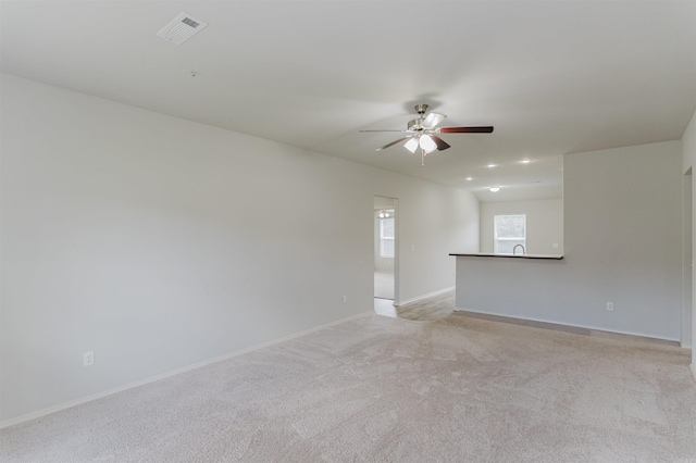 unfurnished room featuring sink, light carpet, and ceiling fan