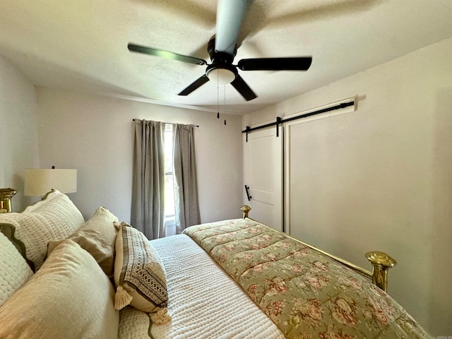 bedroom with a barn door and ceiling fan