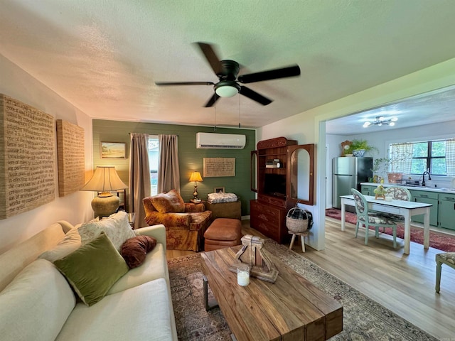 living room with hardwood / wood-style flooring, an AC wall unit, a textured ceiling, and ceiling fan