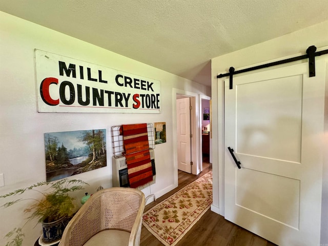 interior space featuring dark wood-type flooring, a barn door, and a textured ceiling