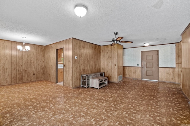 interior space featuring wood walls, a textured ceiling, and parquet flooring