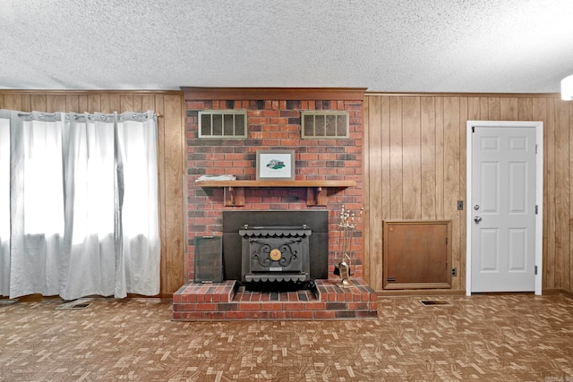 living room featuring brick wall, wood walls, a textured ceiling, and a fireplace