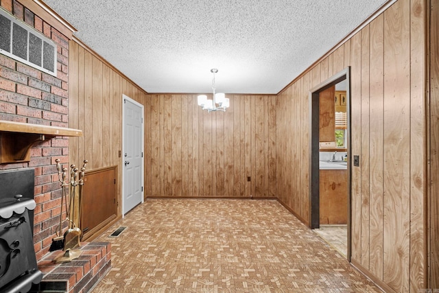 interior space with sink, wood walls, a textured ceiling, and a notable chandelier