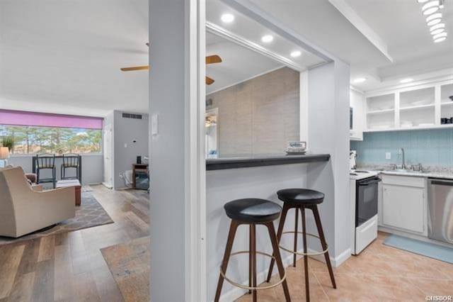 kitchen featuring white cabinets, decorative backsplash, stainless steel dishwasher, ceiling fan, and white range with electric cooktop