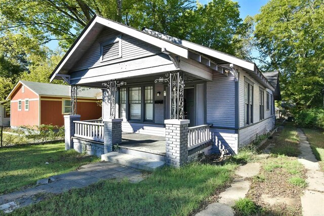 view of front of house with covered porch and a front lawn