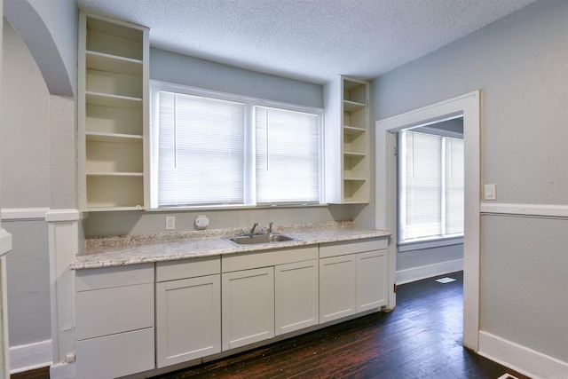 kitchen featuring white cabinetry, sink, a textured ceiling, and dark hardwood / wood-style floors