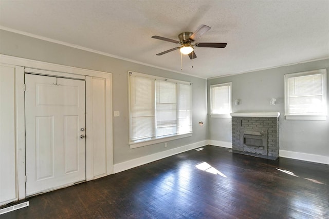 entrance foyer with dark hardwood / wood-style floors, a textured ceiling, a brick fireplace, and a wealth of natural light