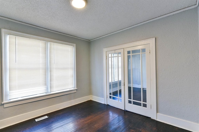 empty room with french doors, dark hardwood / wood-style floors, a textured ceiling, and crown molding