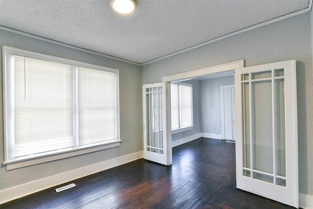 empty room with crown molding, a textured ceiling, dark hardwood / wood-style flooring, and french doors