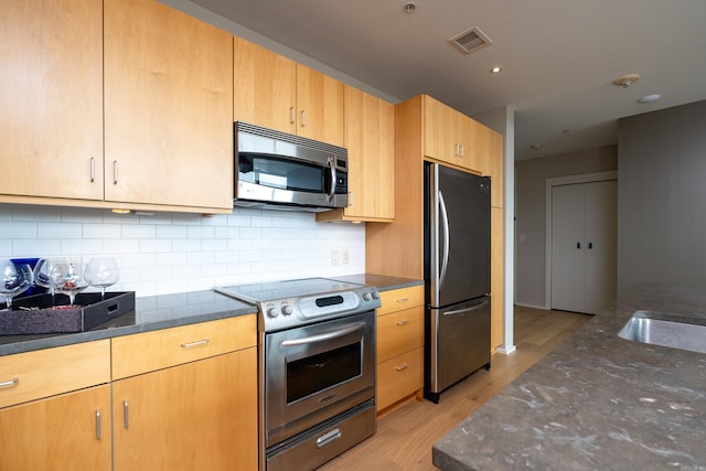 300 Third Unit 708, Little Rock, AR 72201 - kitchen with appliances with stainless steel finishes, dark stone countertops, light wood-style floors, and tasteful backsplash