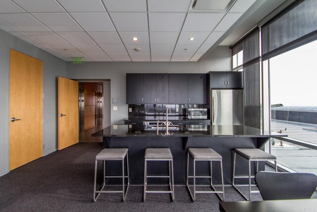300 Third Unit 708, Little Rock, AR 72201 - kitchen featuring appliances with stainless steel finishes, a kitchen bar, dark countertops, a drop ceiling, and recessed lighting