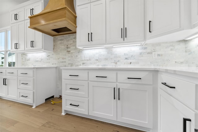 kitchen with tasteful backsplash, light hardwood / wood-style floors, custom range hood, and white cabinets