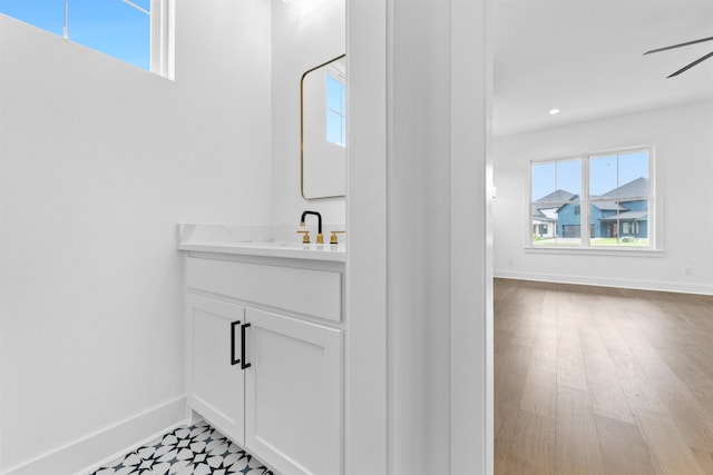 bathroom with ceiling fan, a healthy amount of sunlight, vanity, and hardwood / wood-style flooring