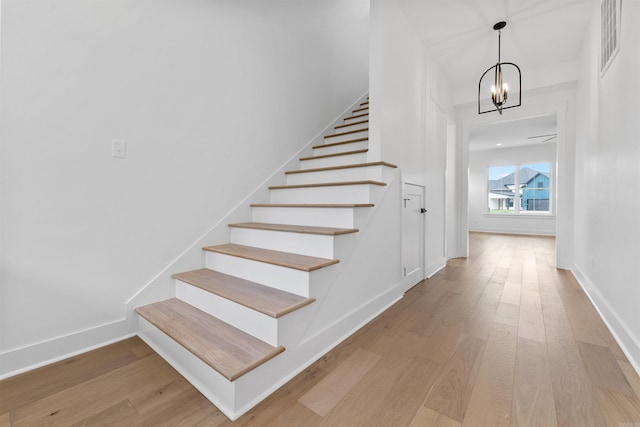 stairway featuring a notable chandelier and wood-type flooring