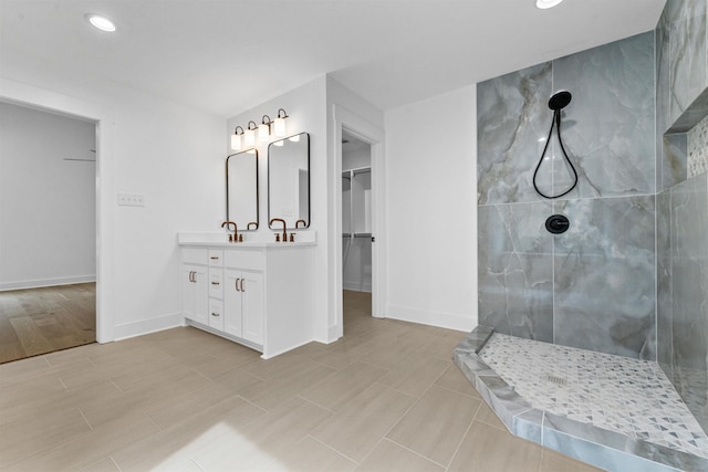 bathroom with a tile shower and vanity