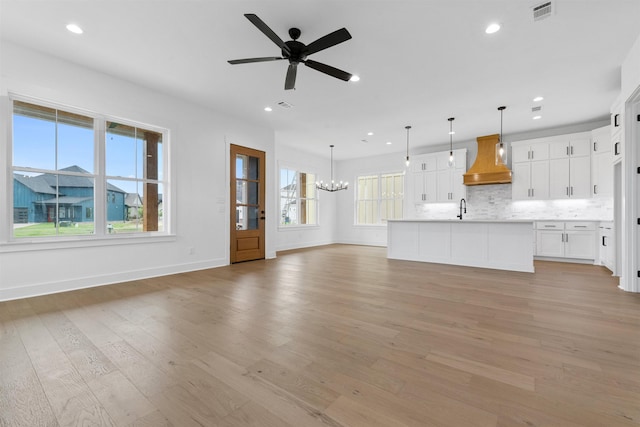 unfurnished living room with sink, light hardwood / wood-style flooring, and a wealth of natural light