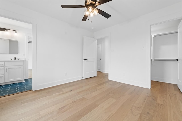 unfurnished bedroom featuring a spacious closet, light hardwood / wood-style flooring, ceiling fan, and a closet