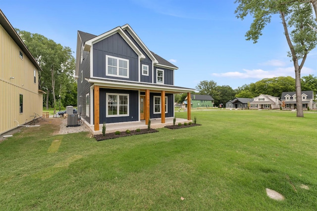 rear view of house with a porch, cooling unit, and a lawn