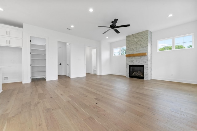 unfurnished living room with ceiling fan, a healthy amount of sunlight, a fireplace, and light hardwood / wood-style flooring