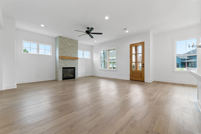 unfurnished living room with ceiling fan, a fireplace, and light hardwood / wood-style flooring