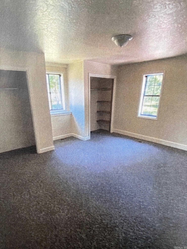 additional living space featuring a healthy amount of sunlight and dark colored carpet