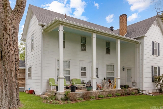 1201 S Reine St, Mena, AR 71953 - back of house with a yard, a shingled roof, a chimney, and a patio area