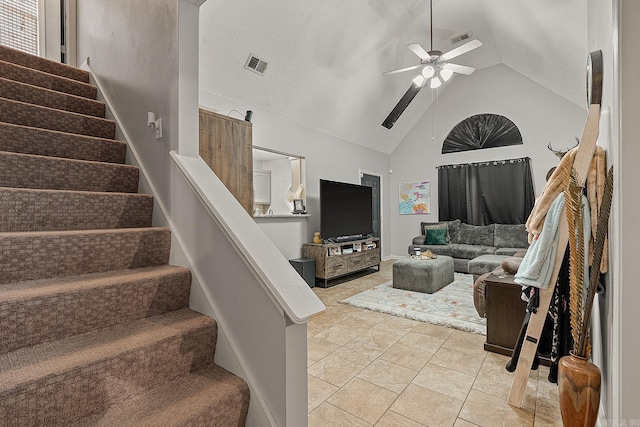 stairs featuring ceiling fan, tile patterned floors, and high vaulted ceiling