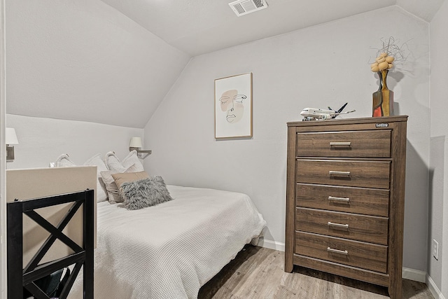 bedroom with lofted ceiling and light wood-type flooring