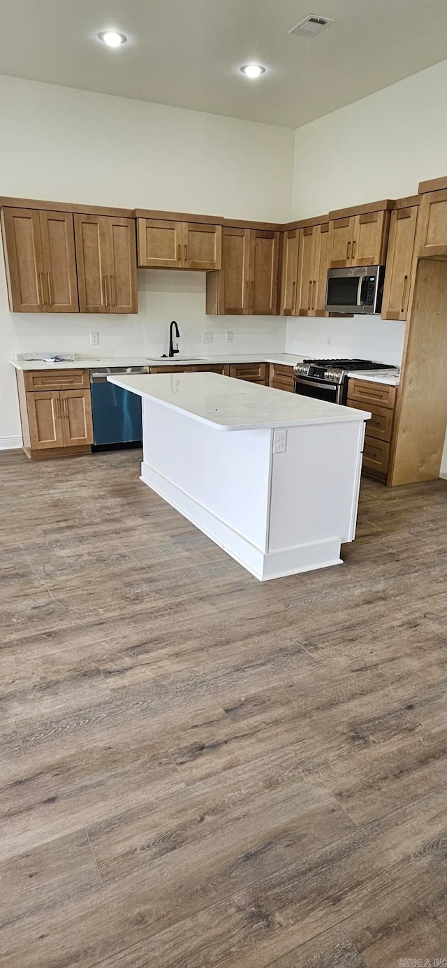 kitchen featuring a kitchen island, stainless steel appliances, sink, and hardwood / wood-style floors