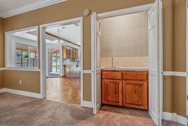 kitchen with pendant lighting, crown molding, backsplash, light carpet, and a chandelier