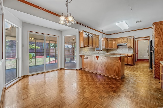 kitchen featuring tasteful backsplash, hanging light fixtures, a breakfast bar area, and parquet floors