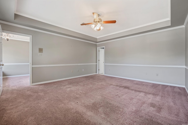 carpeted empty room with a raised ceiling, ornamental molding, and ceiling fan