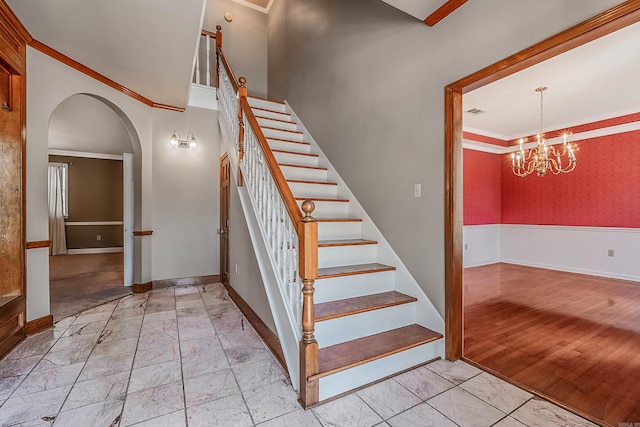 stairway featuring a notable chandelier and ornamental molding