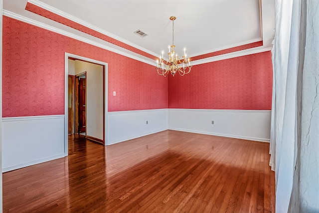 empty room with ornamental molding, wood-type flooring, and a chandelier