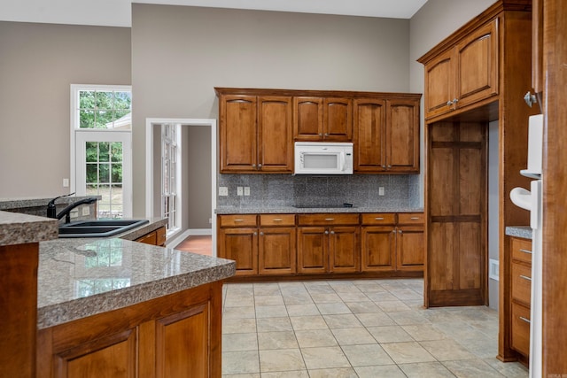 kitchen with black electric cooktop, sink, decorative backsplash, and light tile patterned floors