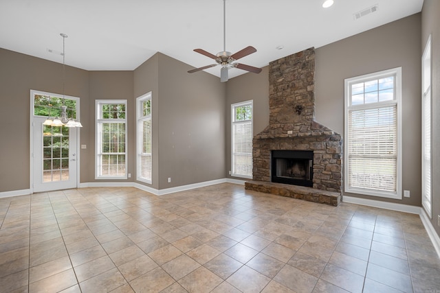 unfurnished living room featuring a stone fireplace, ceiling fan with notable chandelier, and light tile patterned floors