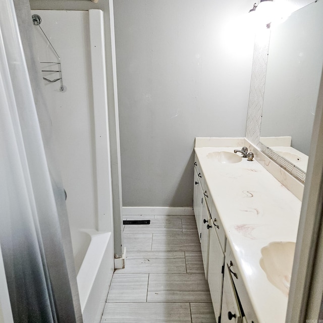 bathroom featuring dual vanity, washtub / shower combination, and tile patterned floors