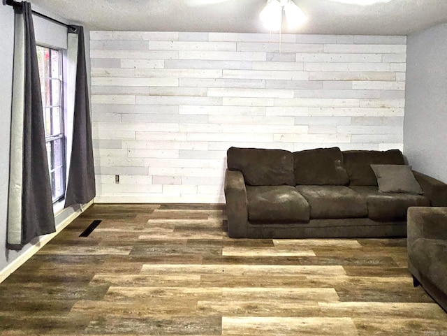 living room with wood-type flooring, brick wall, and a textured ceiling